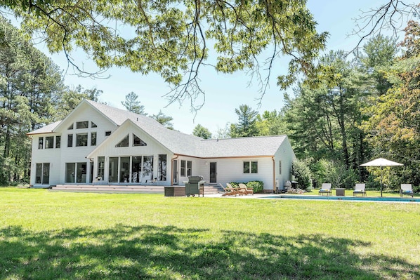 A two-story house with a large front porch, a swimming pool, and a well-maintained lawn. - St. Michaels Waterfront Home with Pool (Saint Michaels)