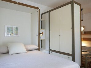 Ein Schlafzimmer mit Bett, Kleiderschrank, Nachttisch mit Lampe und einem Gemälde an der Wand.