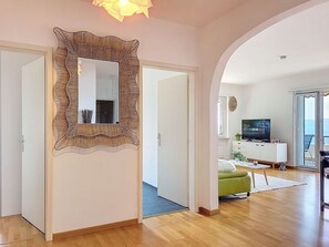 Ein geräumiger Wohnbereich mit einem großen Spiegel, einem Fernseher und einem grünen Ottomanen.