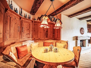 Una cocina de madera con banco integrado, lámparas colgantes y una mesa redonda de madera con tazas.