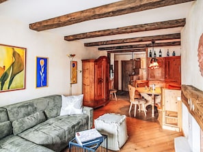 Una sala de estar acogedora con un sofá, una mesa de comedor de madera y una zona de cocina con armarios de madera.