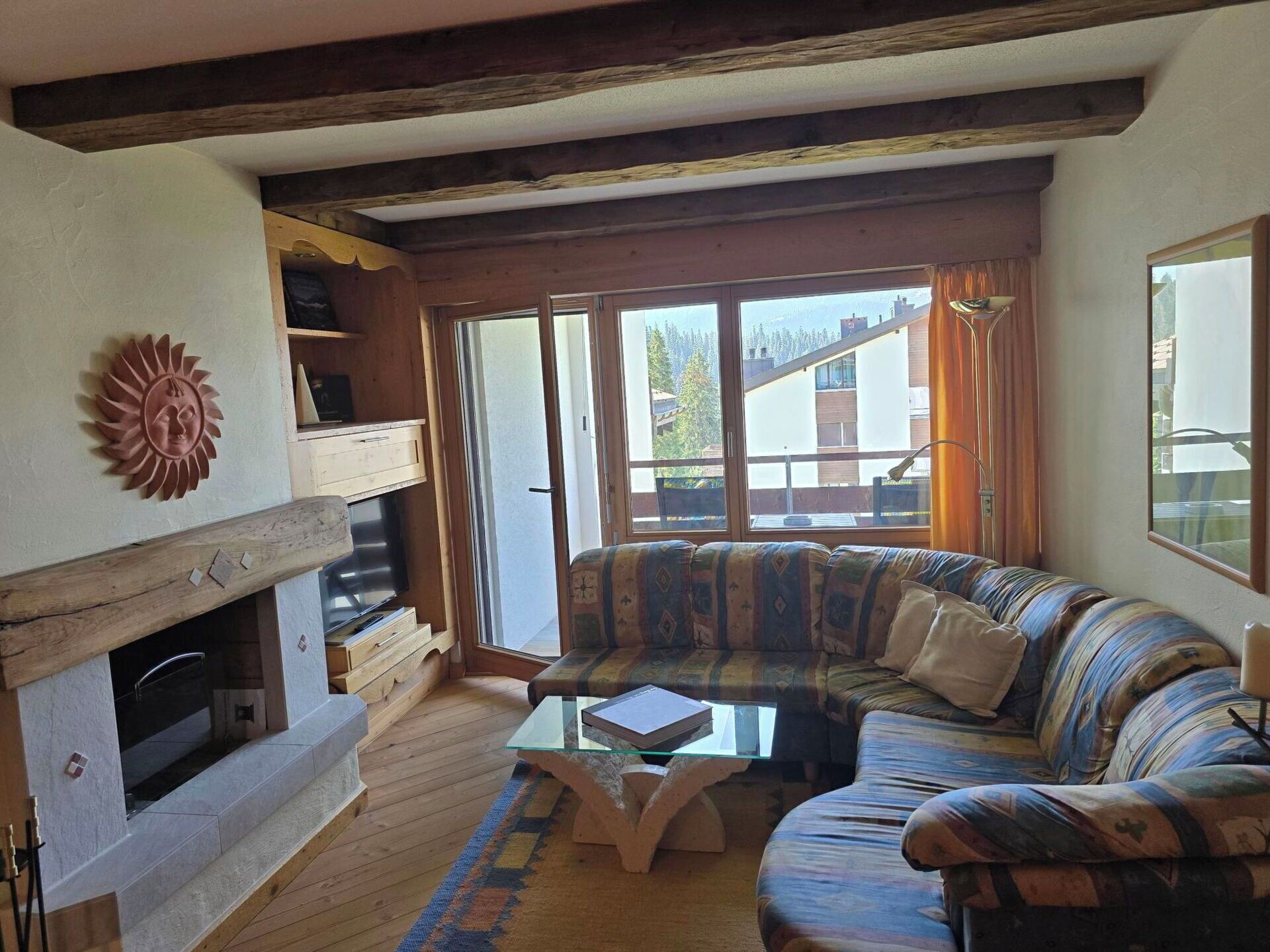 A living room with a fireplace, a sofa, a glass coffee table, and a view through large windows.
