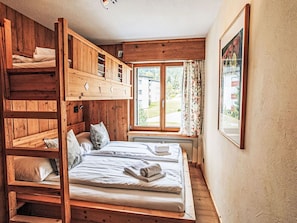 Dormitorio con literas, ventana, paredes de madera y un cuadro enmarcado.