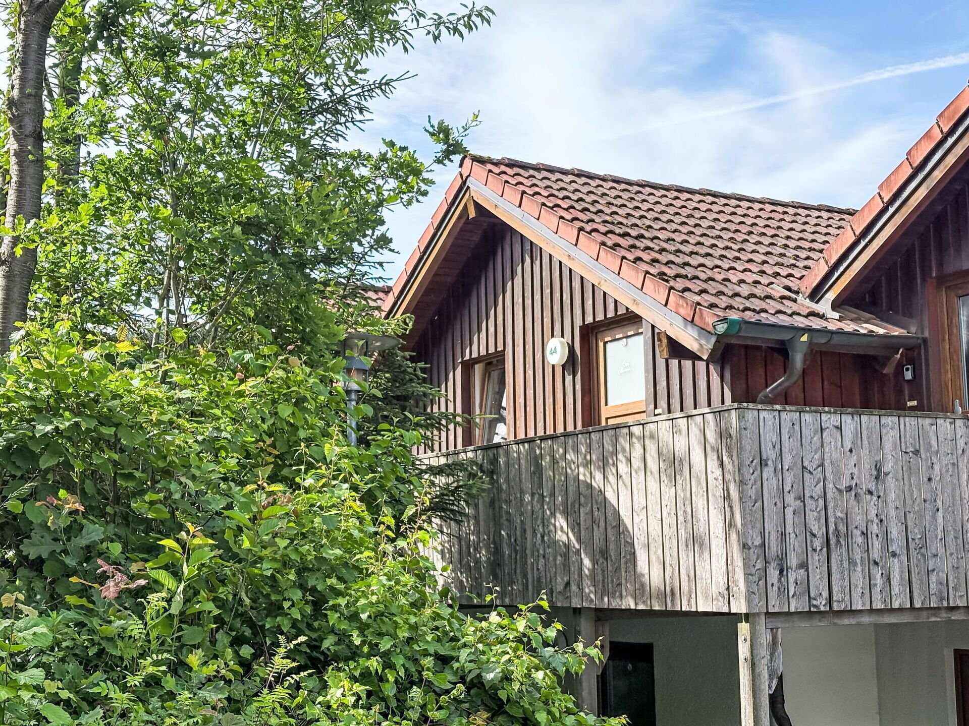 Ein Holzhaus mit geneigtem Dach, einem Balkon und einem Schild mit der Nummer 44.