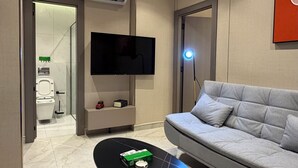 A modern living room with a flat-screen TV, a grey sofa, a black coffee table, and a tiled floor. - 306 Tara-jre 2bedroom at Jabal Al Lweibdeh (Amman)