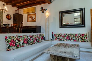 A living room with a sofa, a coffee table, a wooden cabinet, a map, and a mirror. - Bright 1BR Royal Palms condo (Playa Del Carmen)