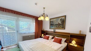 Une chambre à coucher avec un lit, deux lampes de chevet, un tableau et une fenêtre avec des rideaux.
