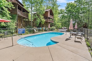 A pool area with lounge chairs, a sign indicating pool rules, and a wooden building with a balcony. - Venus 151 2 Bedroom Condo (Gatlinburg)