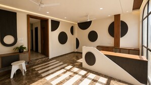 A modern reception area with a check-in desk, a seating area, and a staircase. - Benchmark Stays (Indore)