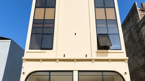 A two-story building with large windows, a staircase, and a small outdoor seating area. - Benchmark Stays (Indore)