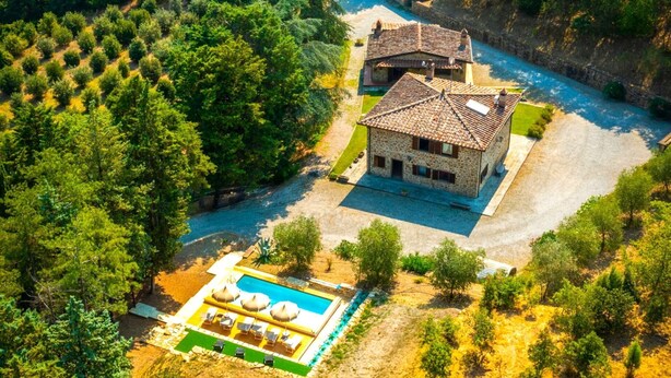 Una villa de piedra con piscina y un río.