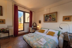 Ein Hotelzimmer mit einem Bett, einem Schreibtisch, einem Stuhl, einem Fenster mit Vorhängen und einem Bild an der Wand.