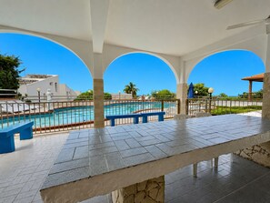 Ein überdachter Außenbereich mit Pool, Bänken und Meerblick.