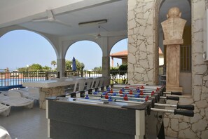 Ein Poolbereich mit einer Tischfußballplatte, Liegestühlen und einer Steinsäule.