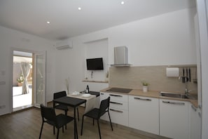 Eine moderne Küche mit Essbereich, Flachbildfernseher und Backofen.