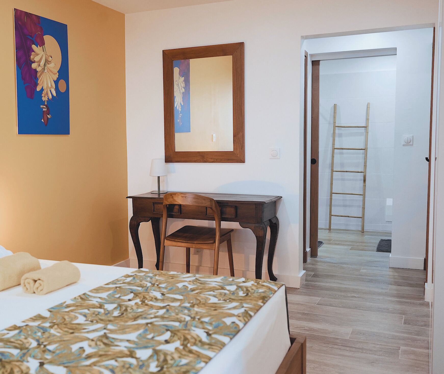 Ein Hotelzimmer mit Bett, Schreibtisch, Stuhl und einer Tür zu einem Flur mit einer Wendeltreppe.