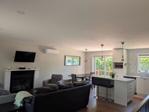 A modern living room with a fireplace, a flat-screen TV, a sofa, and a dining area with a kitchen in the background. - Cozy full home in Laval - 5mn from Golf, access to airport, Montreal (Laval)
