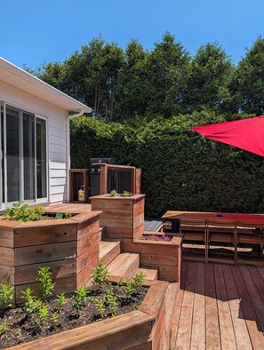 A wooden deck with raised planters, a barbecue grill, and a red umbrella. - Cozy full home in Laval - 5mn from Golf, access to airport, Montreal (Laval)