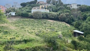 A hilly landscape with scattered buildings, dense vegetation, and a small structure on the slope. - Apartment with atypical view of Bergerie (Bastia)