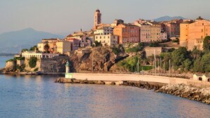 A coastal town with historic buildings, a lighthouse, and a rocky shoreline. - Apartment with atypical view of Bergerie (Bastia)
