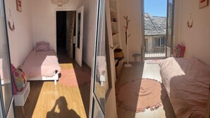 A bedroom with a bed, a small table, a chair, a window, and a door leading to another room. - Apartment with atypical view of Bergerie (Bastia)