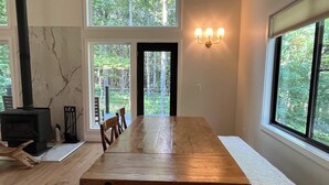 Uma sala de jantar ampla com uma longa mesa de madeira, várias cadeiras, um banco e uma lareira.