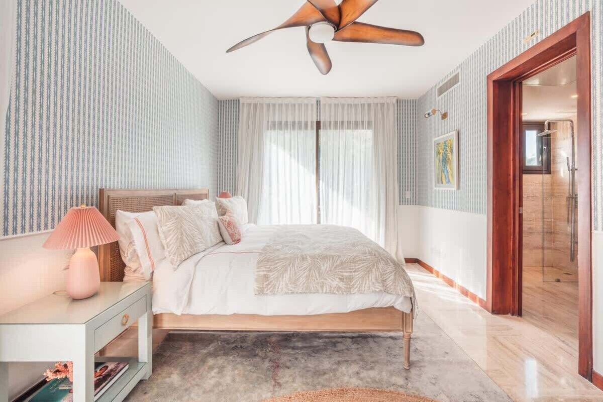 Ein Schlafzimmer mit Bett, Nachttisch, Lampe und Deckenventilator.