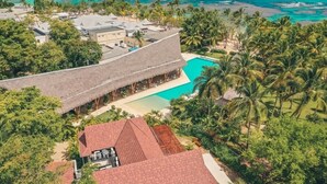 Ein Resort mit Pool, strohgedeckten Gebäuden und Palmen.