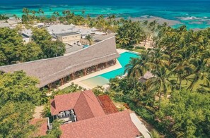 Ein Resort mit Pool, strohgedeckten Gebäuden und Palmen.