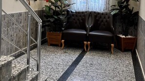 Un vestíbulo con una araña, un sofá, una escalera y una planta en maceta.