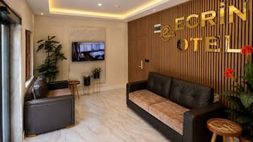 A hotel lobby with a sofa, a television, and a reception desk.