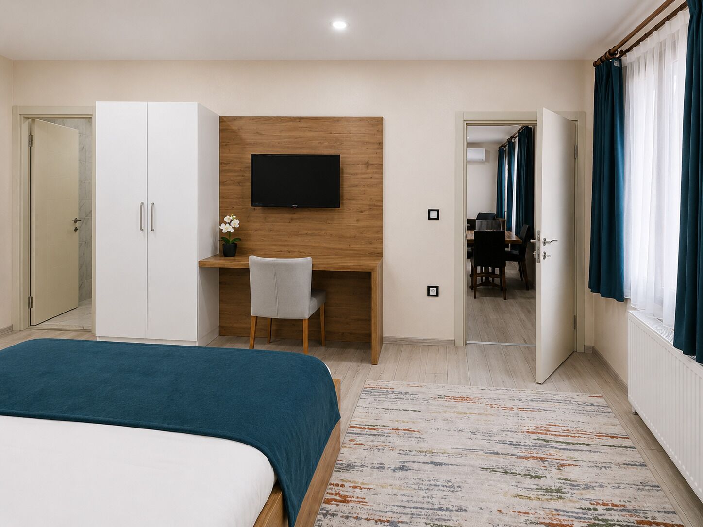 A hotel room with a bed, a desk with a chair, a TV, and a bathroom visible through an open door.