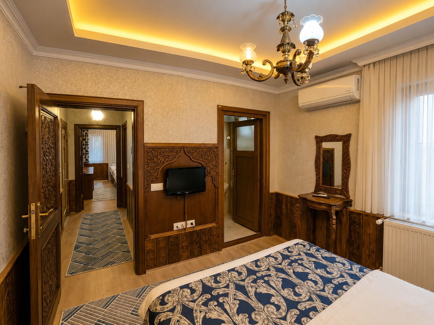 Une chambre d’hôtel équipée d’un lit, d’une télévision, d’un miroir, d’un lustre et d’un appareil de climatisation.