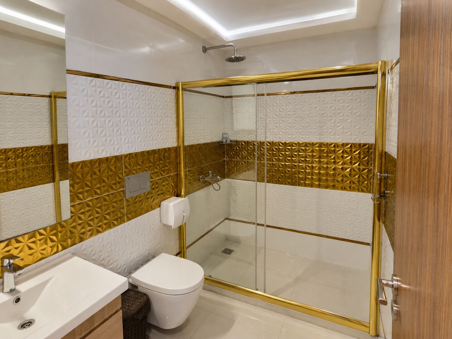 Un baño moderno con ducha de vidrio, lavamanos blanco y un inodoro.