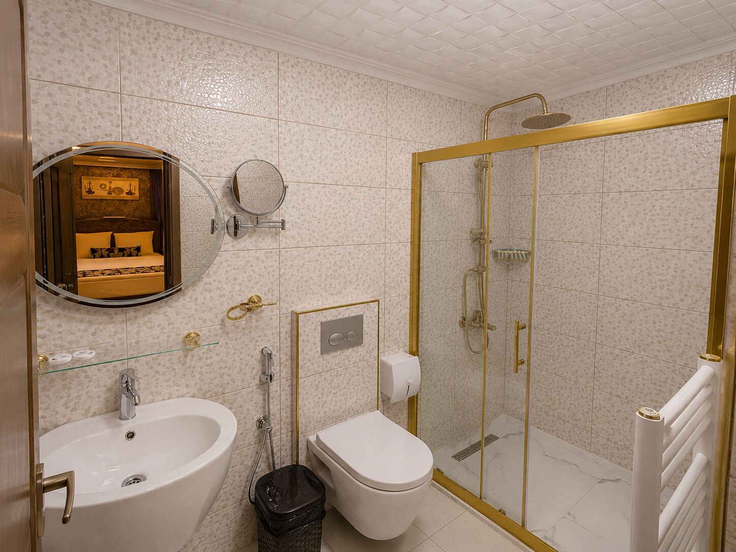 A bathroom with a shower, toilet, sink, and a mirror with a decorative frame.