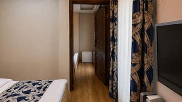 A hotel room with a bed, a desk with a printer, and a TV.