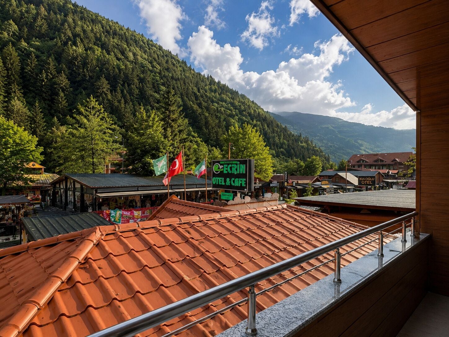 Een hotel met een terracottadak, een naambord en vlaggen.