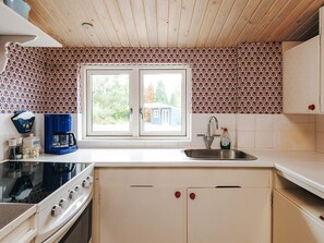 A kitchen with a double sink, a coffee maker, and a stove. - 6 Person Holiday Home in Vaeggerlose (Vaeggerlose)