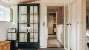 A room with a black cabinet with glass doors, a wooden ceiling, and a hallway leading to another room. - 6 Person Holiday Home in Vaeggerlose (Vaeggerlose)