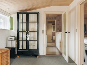 A room with a black cabinet with glass doors, a wooden ceiling, and a hallway leading to another room. - 6 Person Holiday Home in Vaeggerlose (Vaeggerlose)