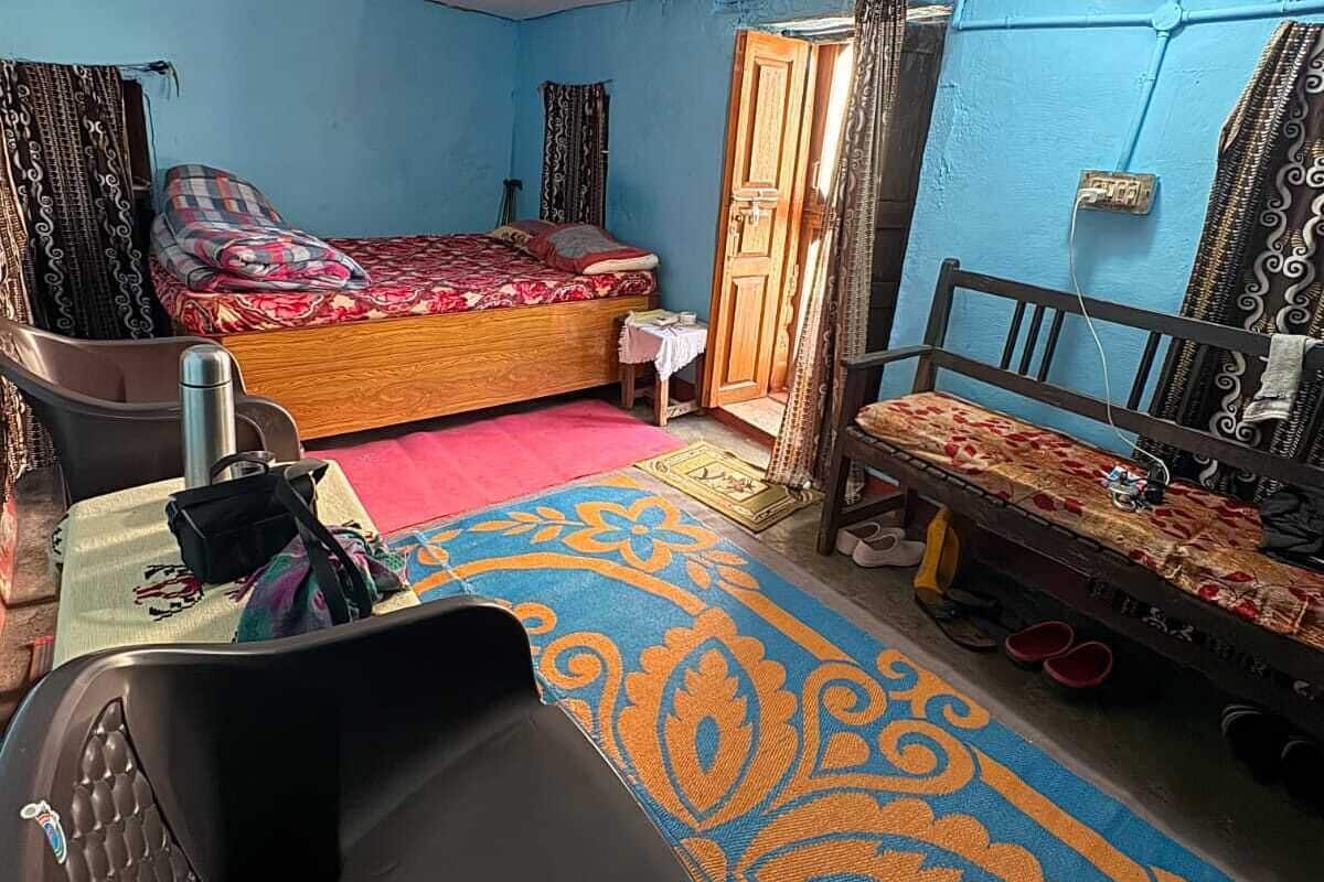 A compact room with a bed, a chair, a small table, and a door.