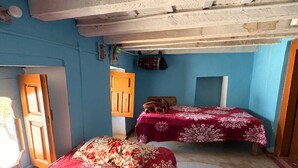 Una habitación con dos camas, una puerta de madera y una pared azul.