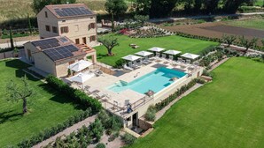A two-story building with a swimming pool, outdoor seating, and solar panels.