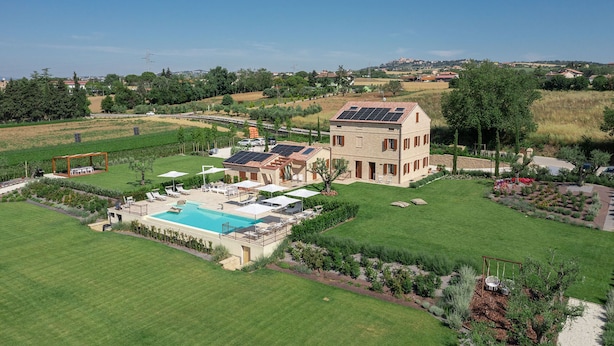 A two-story house with a swimming pool, solar panels, and a well-maintained lawn.
