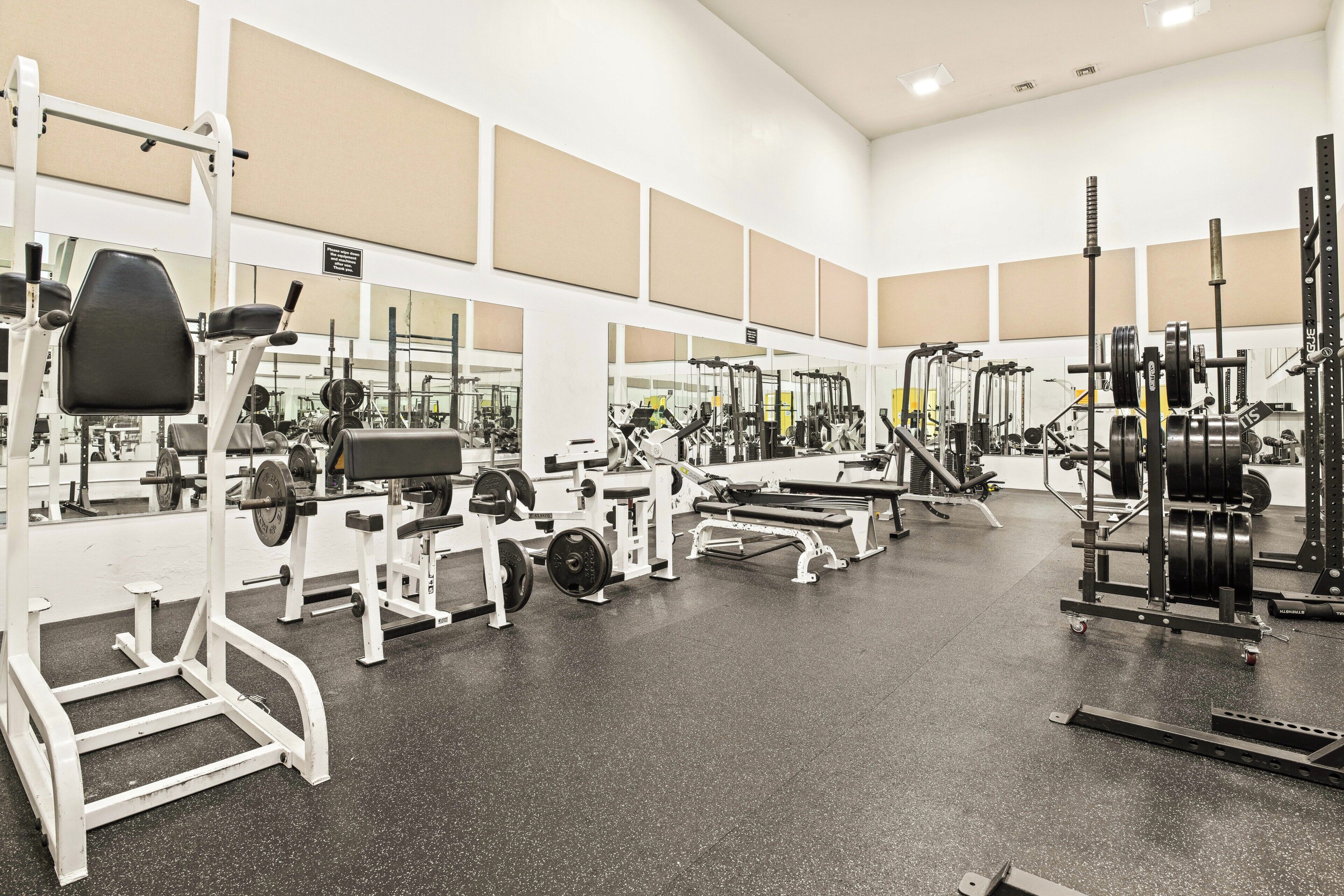 A gym with various exercise equipment, mirrors, and a clean, spacious layout.