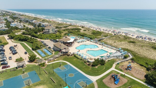 Ein Resort mit großem Poolbereich, einem Basketballplatz und einem Strand.