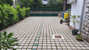 A paved courtyard with a green metal gate, potted plants, and a stone wall. - One bedroom apartment with balcony and garden view (Selce)