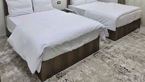 Een hotelkamer met twee bedden, een kamerbreed tapijt met dessin en moderne verlichting.