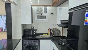 Een praktische keuken met een wasmachine, een magnetron, een fornuis en een koelkast.