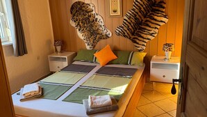 Een kamer met een bed, twee nachtkastjes, een hoofdbord met luipaardprint en een deur.